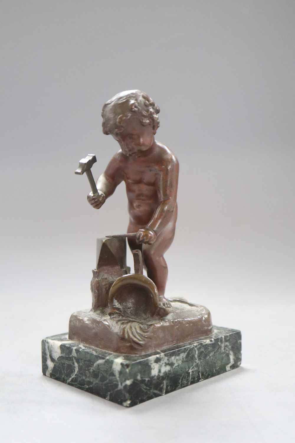 A bronze putto blacksmith, signed H. Capy, on marble base, height 15cm